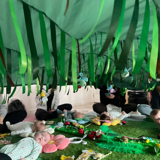 Evergreen Sensory Parachute™ in use during a baby class, with green ribbons flowing as the parachute moves.
