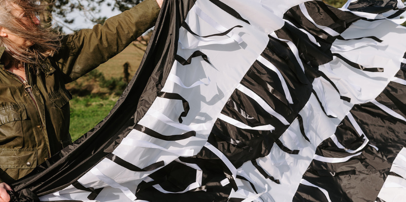 Black and white sensory parachute held up by a woman, showing part of her hair and arm