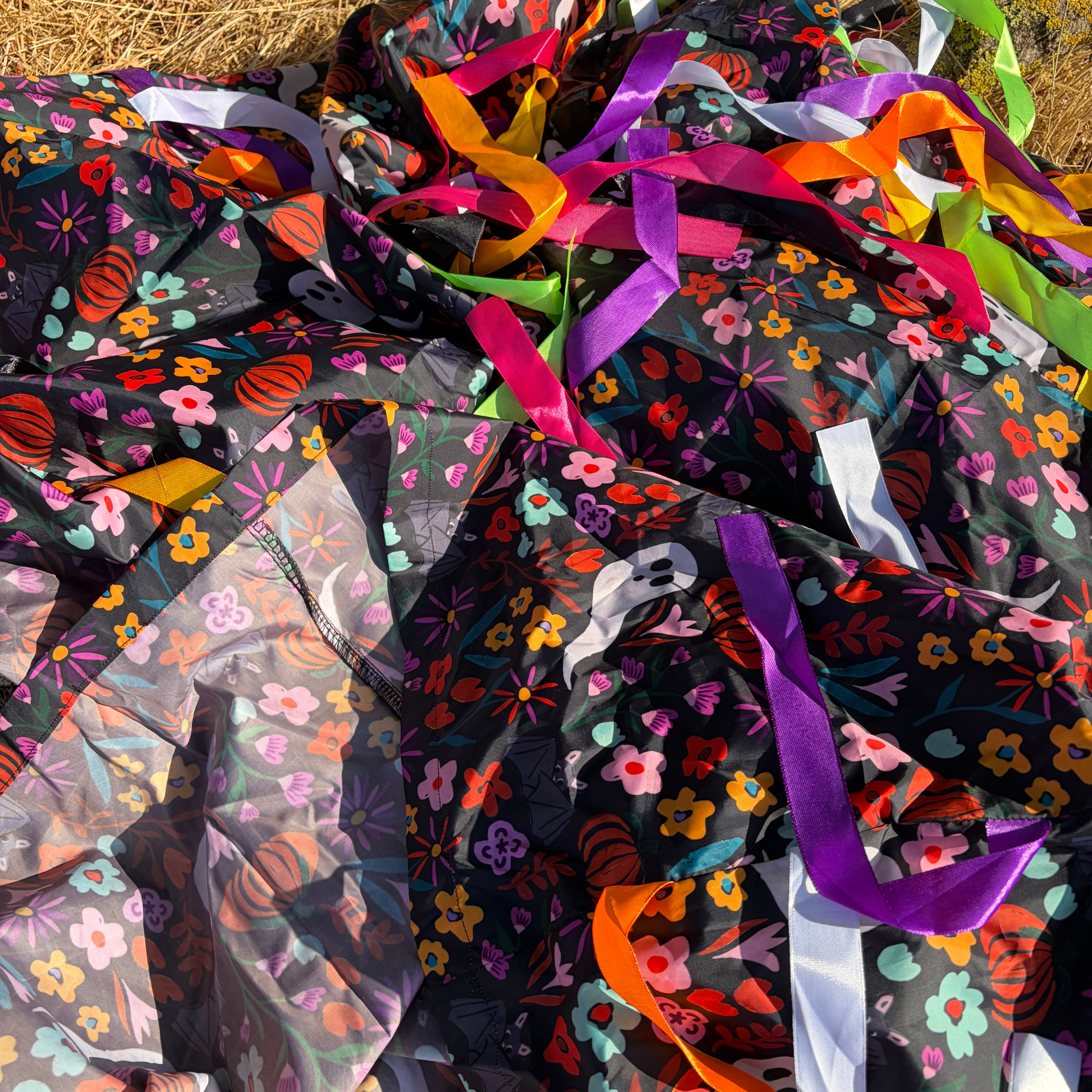 close up of midnight garden sensory parachute, green, purple, pink, orange, white, black, yellow ribbons on a custom printed fabric 
