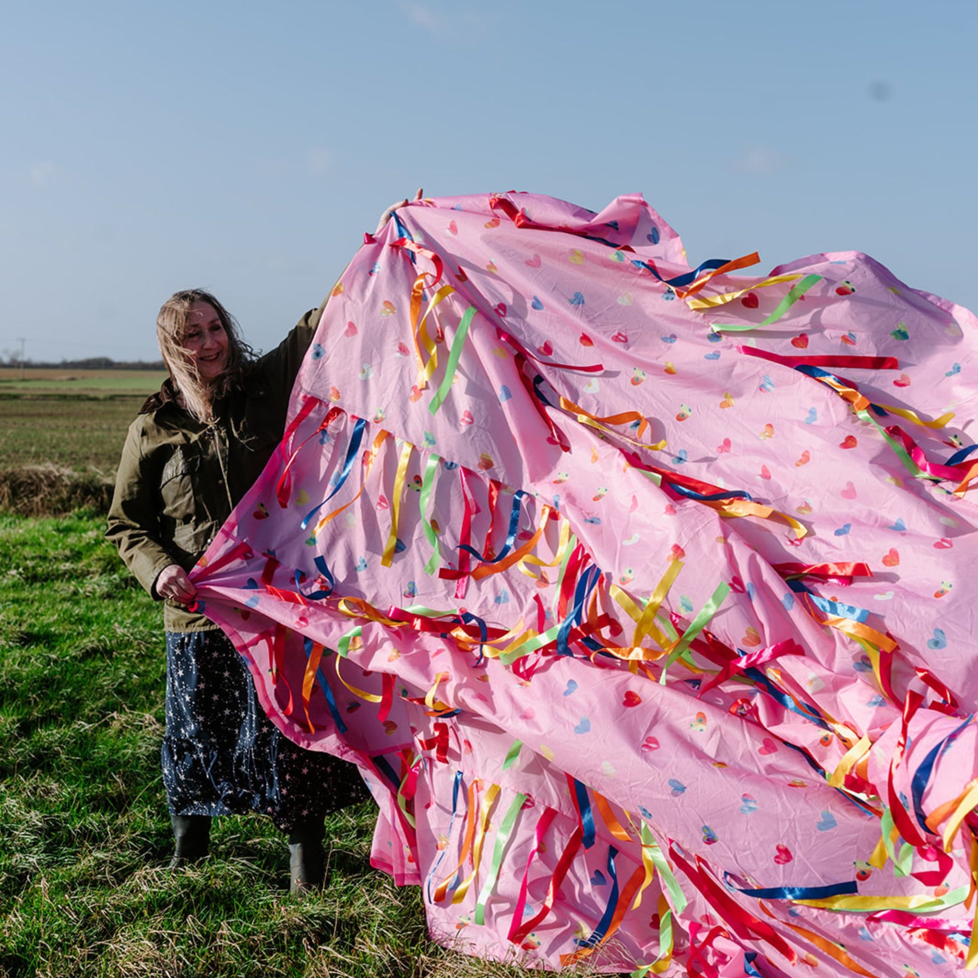 Elizabeth holding the Love is in the Air pink Sensory Parachute outdoors, showing the full 3m parachute with colourful ribbons