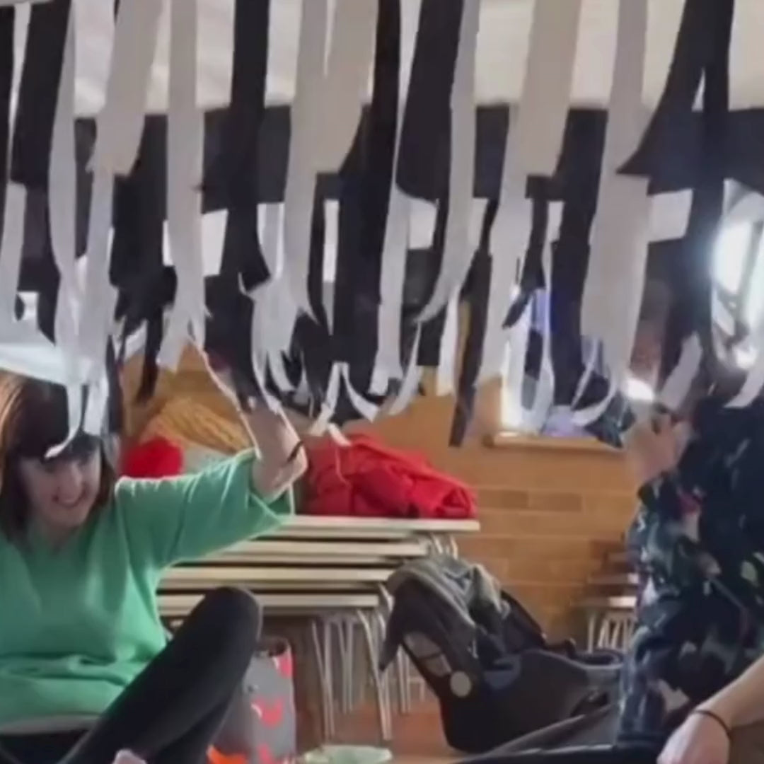 Black & White Sensory Parachute in motion, with over 200 shimmering black and white ribbons flowing during a baby class activity.