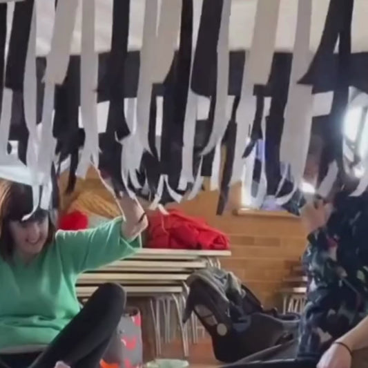 Black & White Sensory Parachute in motion, with over 200 shimmering black and white ribbons flowing during a baby class activity.