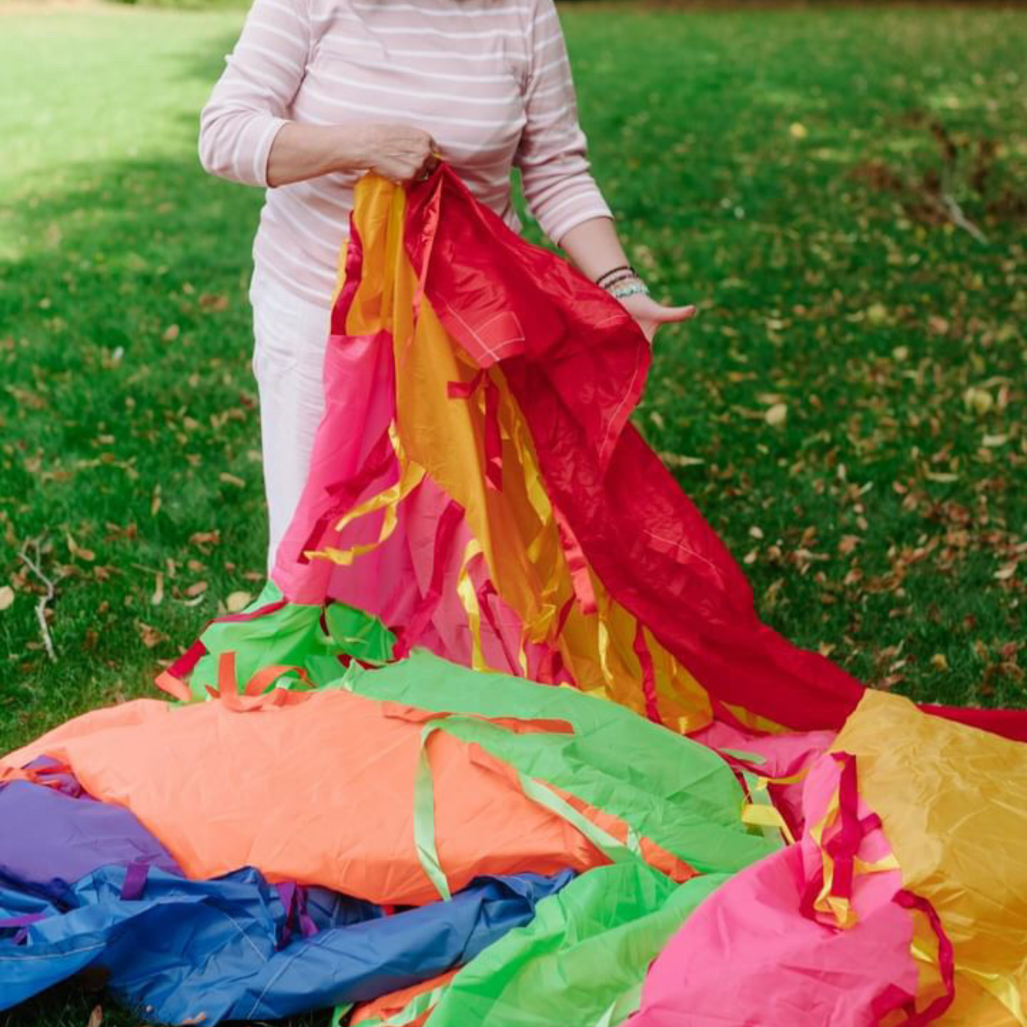 Preparing and folding a rainbow sensory parachute, handmade for baby development and movement classes